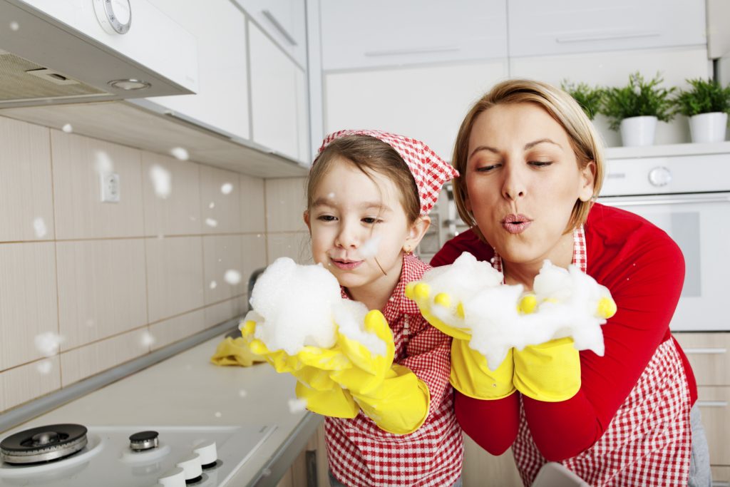 enseñar a los niños a ser ordenados: imagen de una madre jugando con la espuma de fregar con su hija